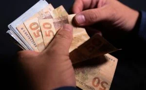 Portal Fio Diário 10 Homem mexendo em notas de dinheiro para representar Imposto de Renda